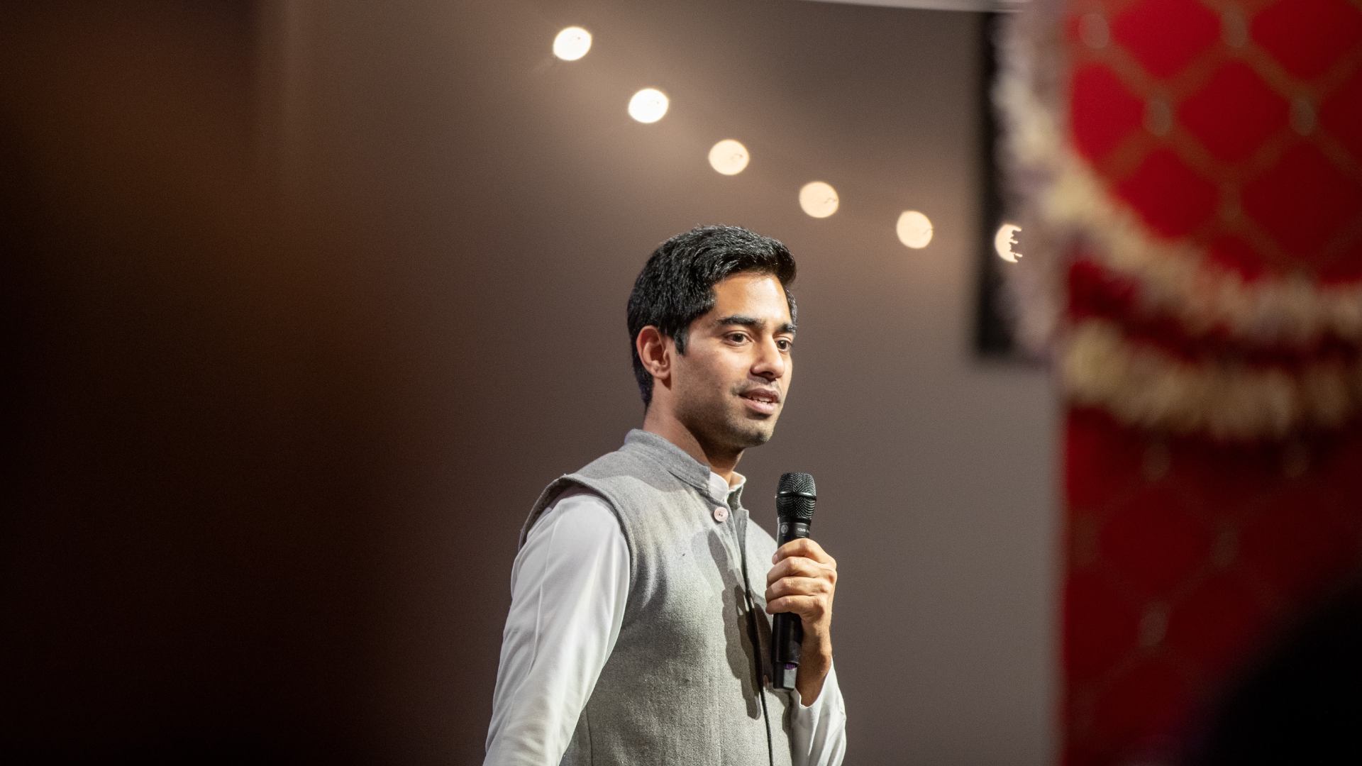 Yogesh Singh speaking on stage wearing traditional Indian clothes
