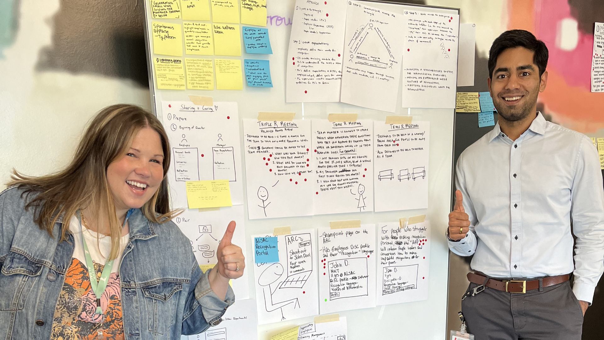 Yogesh Singh posing "thumbs-up" with a coworker in front of a Design Thinking idea board with handwritten notes and stickies.