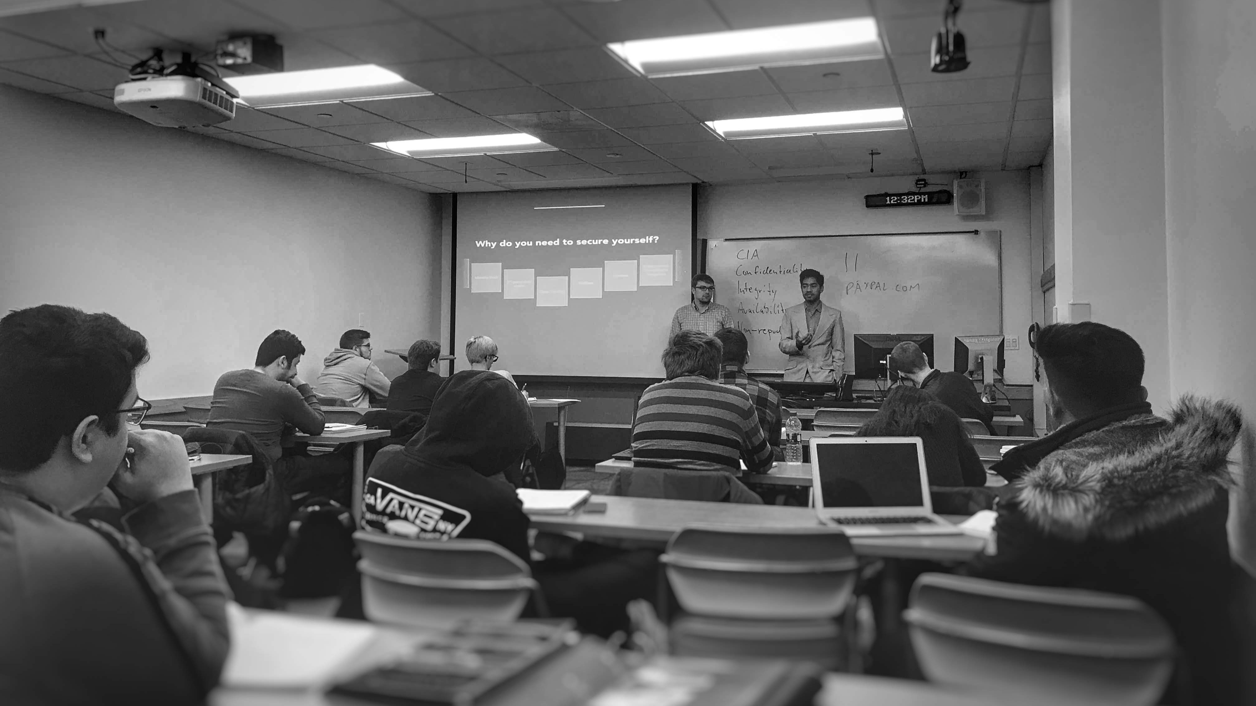 Yogesh Singh delivering a lecture on cybersecurity to a class with his friend.